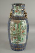 A CHINESE BLUE GROUND GILDED FAMILLE VERTE PORCELAIN VASE, on a hardwood stand, painted with two