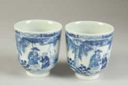 A PAIR OF CHINESE BLUE AND WHITE PORCELAIN CUPS, painted with a fishing scene, the bases with four-
