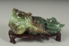 A CHINESE CARVED JADE FIGURE OF AN ELEPHANT ON A FITTED CARVED HARDWOOD STAND, figure 14cm long.