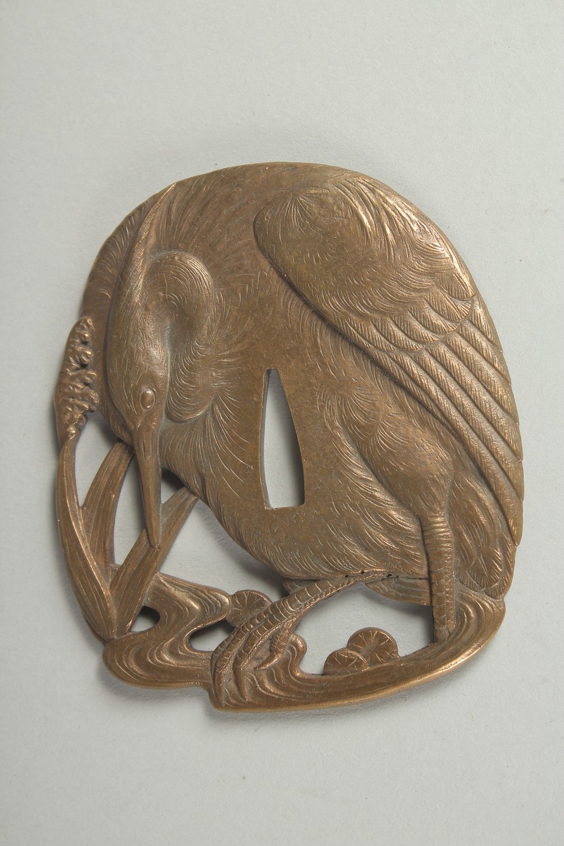 A JAPANESE ENGRAVED BRASS OPENWORKED TSUBA, designed with an egret, 9.5cm x 8cm.