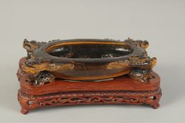 A FINE AND UNUSUAL CHINESE CARVED TIGER'S EYE BRUSH WASHER, on a fitted carved hardwood stand, of