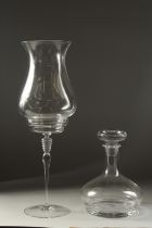 A TALL PLAIN CLASS STORM LAMP ON STAND. 18ins high and a plain ships decanter and stopper.