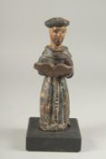 A 17TH CENTURY CARVED WOOD AND PAINTED MONK holding a book. 8ins high.