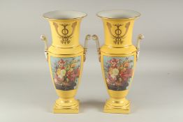 A PAIR OF SEVRES STYLE YELLOW GROUP TWO HANDLED PORCELAIN VASES with reverse panels of flowers.