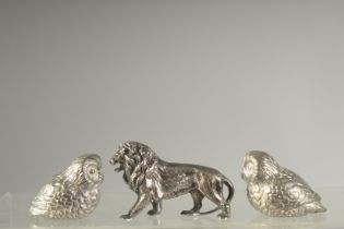 A CAST SILVER LION, 2ins long and TWO CAST PLATE OWLS (3).