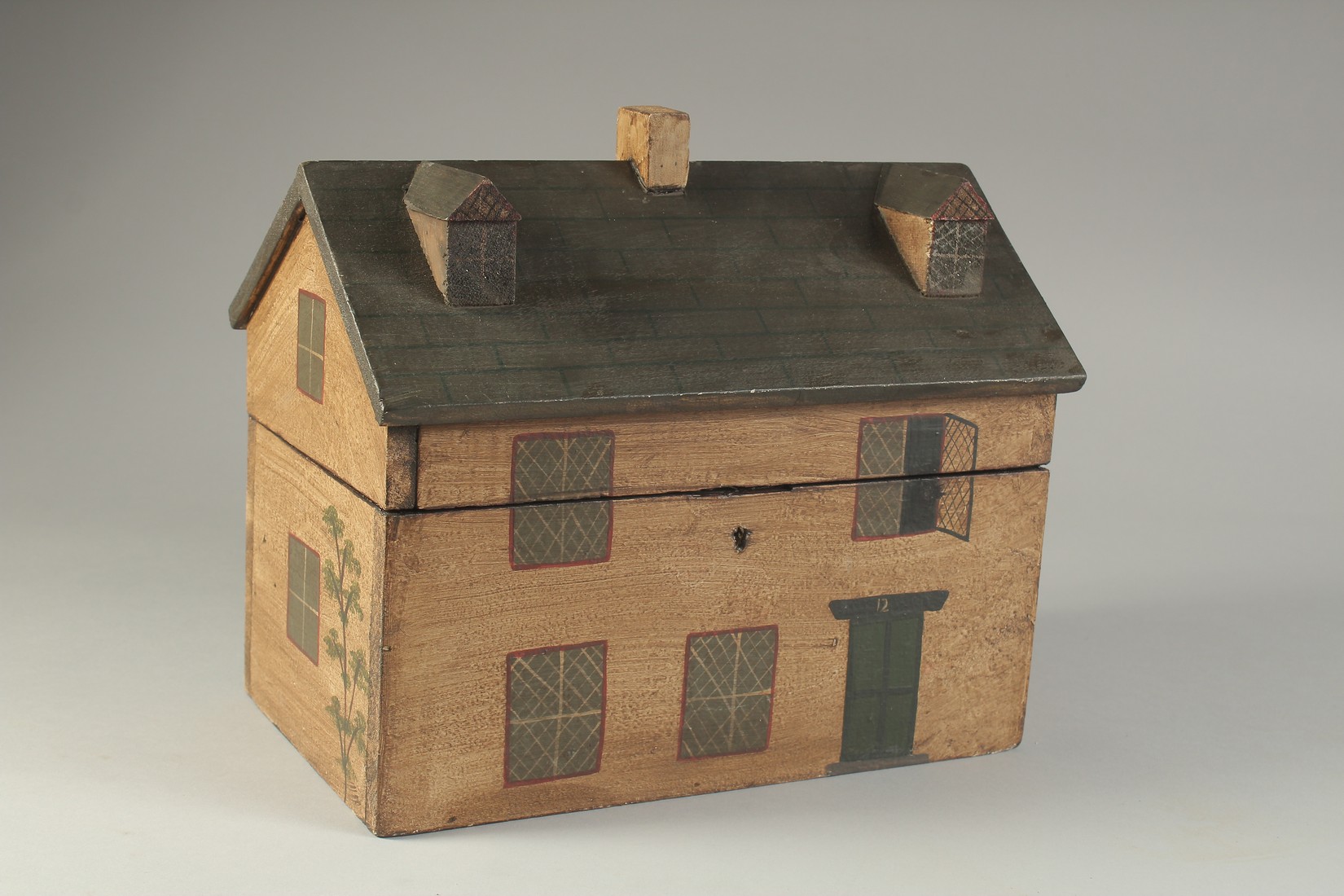 A DECORATIVE PAINTED BOX OR TEA CADDY, modelled as a cottage. 10ins long.