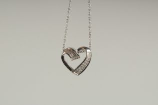 A 14CT WHITE GOLD AND DIAMOND HEART SHAPED PENDANT on a chain.