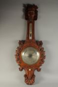 A GOOD 19TH CENTURY WHEEL BAROMETER / THERMOMETER, the well carved wood case with "Green Man"