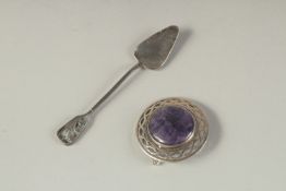 AN ARTS AND CRAFTS CIRCULAR PIERCED LAPIS BROOCH and a spoon.