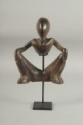 A CARVED AFRICAN OPEN WORK FIGURE. 8ins high on a metal stand.