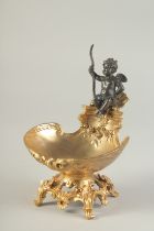 A BRONZE AND GILT BRONZE TABLE SALT modelled as a cherub, seated on a shell shaped dish. 7ins high.