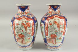 A PAIR OF IMARI PORCELAIN VASES with panels of flowers and birds. 10ins high.