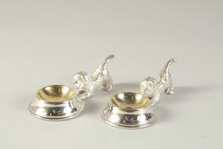 A PAIR OF SILVER PLATED SALTS modelled as puppies by a bowl.