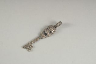 A DIAMOND SET SKULL AND KEY CHARM.