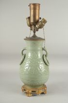 A CHINESE CELEDON PORCELAIN LAMP with ring handles, converted to electricity, on a gilt metal base.