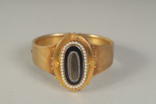 A GOOD 15CT GOLD VICTORIAN MOURNING BANGLE with black enamel and seed pearls