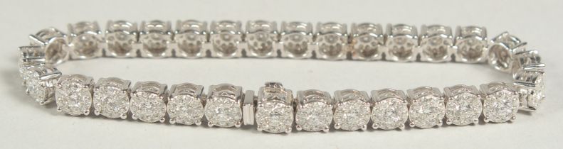 A SUPERB 18 CARAT WHITE GOLD, ILLUSION SET DIAMOND, LINE BRACELET with 30 cluster set diamonds. 20cm