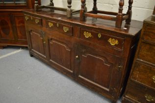 An 18th century oak dresser with three frieze drawers above three panelled doors (replacement draw