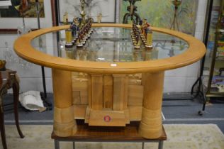 A highly unusual oak chess table, the framed circular glass top supported on a base in the form of a
