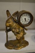 A novelty brass mantel clock modelled as a rabbit carrying some firewood on his back.