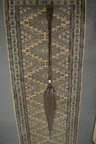 A carved wood spear shaped paddle.