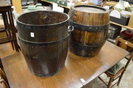A large barrel shaped planter or stick stand together with another large wrought bound oak barrel