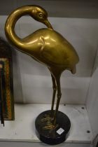 A large cast brass metal figure of a wading bird on a marble base.