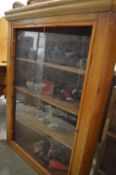 A pine corner cabinet containing a collection of dolls of the world.