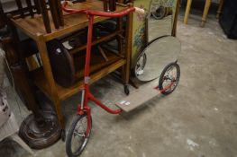 A childs red painted scooter.