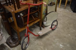 A childs red painted scooter.