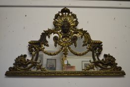 A highly ornate brass over-mantel mirror with female mask, swags, C scrolls etc.