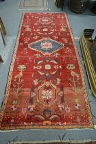 A Persian long carpet, red ground with stylised decoration 259cm x 108cm.