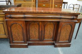 A Victorian mahogany sideboard with three cushion shaped drawers above four panelled doors.