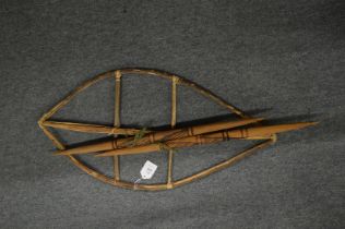 A shield frame and carved wood spears.