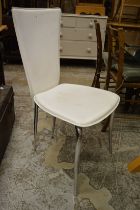 A set of six white leather dining chairs.