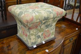 An upholstered concave sided box ottoman.