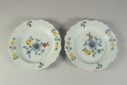 A PAIR OF FLORAL TIN GLAZED PLATES. 9ins diameter.