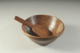 AN EARLY WOODEN CIRCULAR BUTTER BOWL AND SPOON. 8ins diameter.