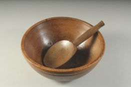 A LARGE WOODEN CIRCULAR BUTTER BOWL AND SPOON. 10ins diameter.