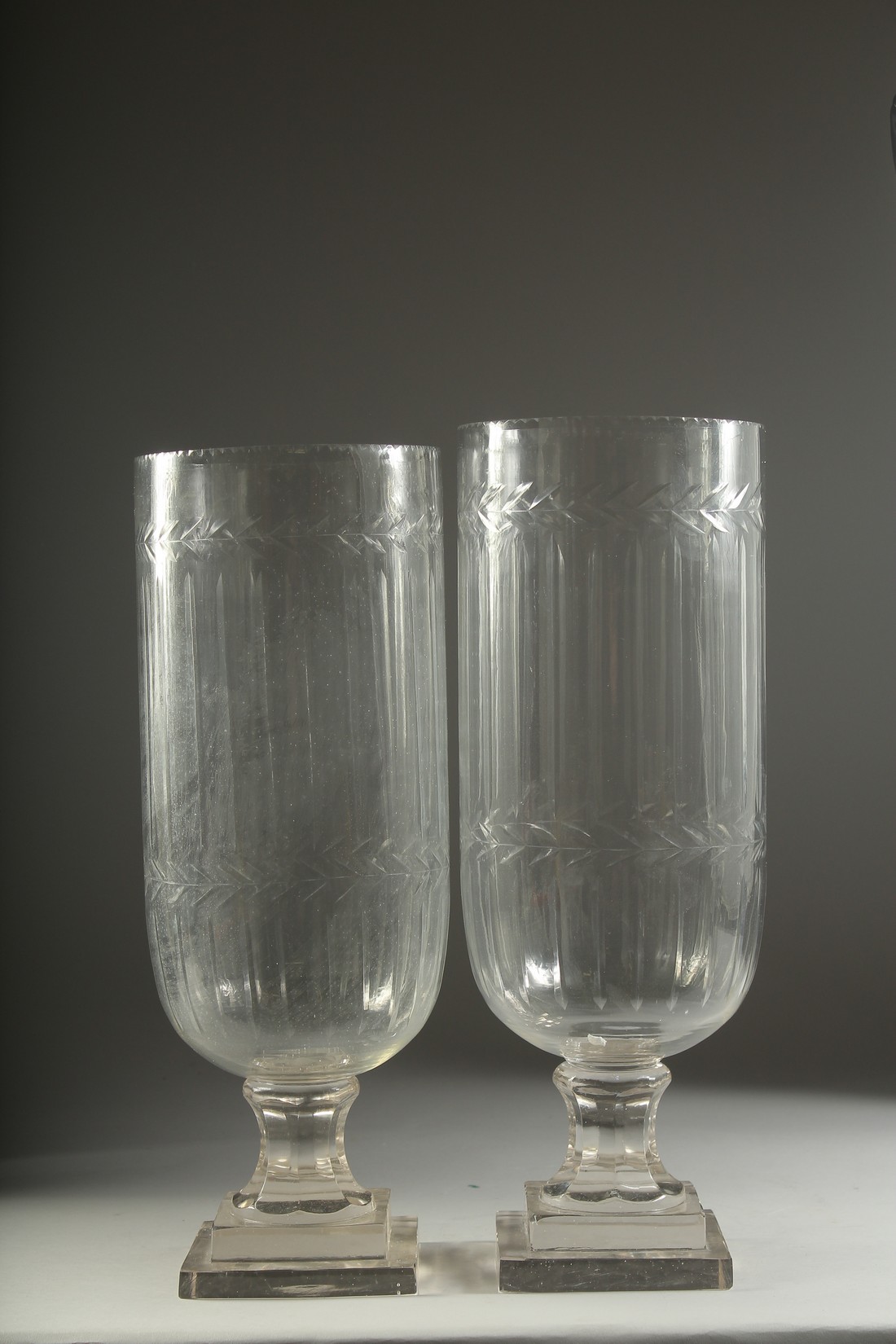 A PAIR OF CUT GLASS HURRICANE LAMPS on square bases. 16ins high.