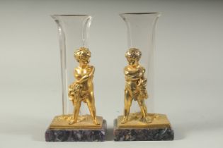 A GOOD PAIR OF GILT BRONZE AND GLASS VASES with cupid design and Blue John bases. 9ins high.