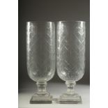 A PAIR OF CUT GLASS HURRICANE LAMPS on square bases. 16ins high.