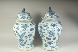 A PAIR OF CHINESE BLUE AND WHITE GINGER JARS AND COVERS decorated with emblems. 18ins high.