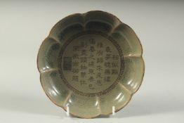 A CHINESE OLIVE GREEN GLAZE PETAL FORM DISH, the interior with characters. 18.5cms wide.