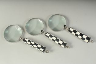 THREE MAGNIFYING GLASSES with chequered handles.