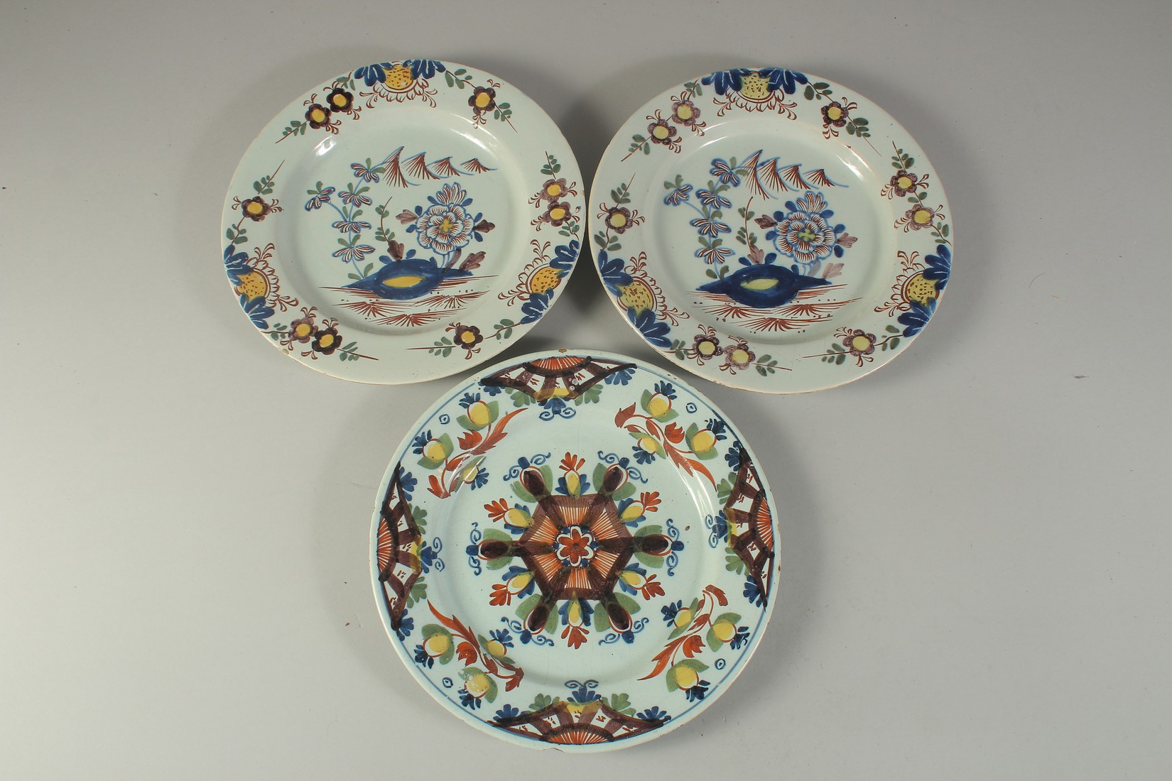 A PAIR OF TIN GLAZE FLORAL PLATES and another similar. 9ins diameter (3).