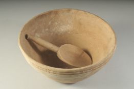 A LARGE WOODEN CIRCULAR BUTTER BOWL AND SPOON. 12ins diameter.