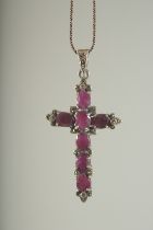 A SILVER AND RUBY SET CROSS on a chain, boxed.