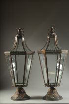 A PAIR OF COPPER METAL GLAZED LANTERNS on circular bases. 27ins high.
