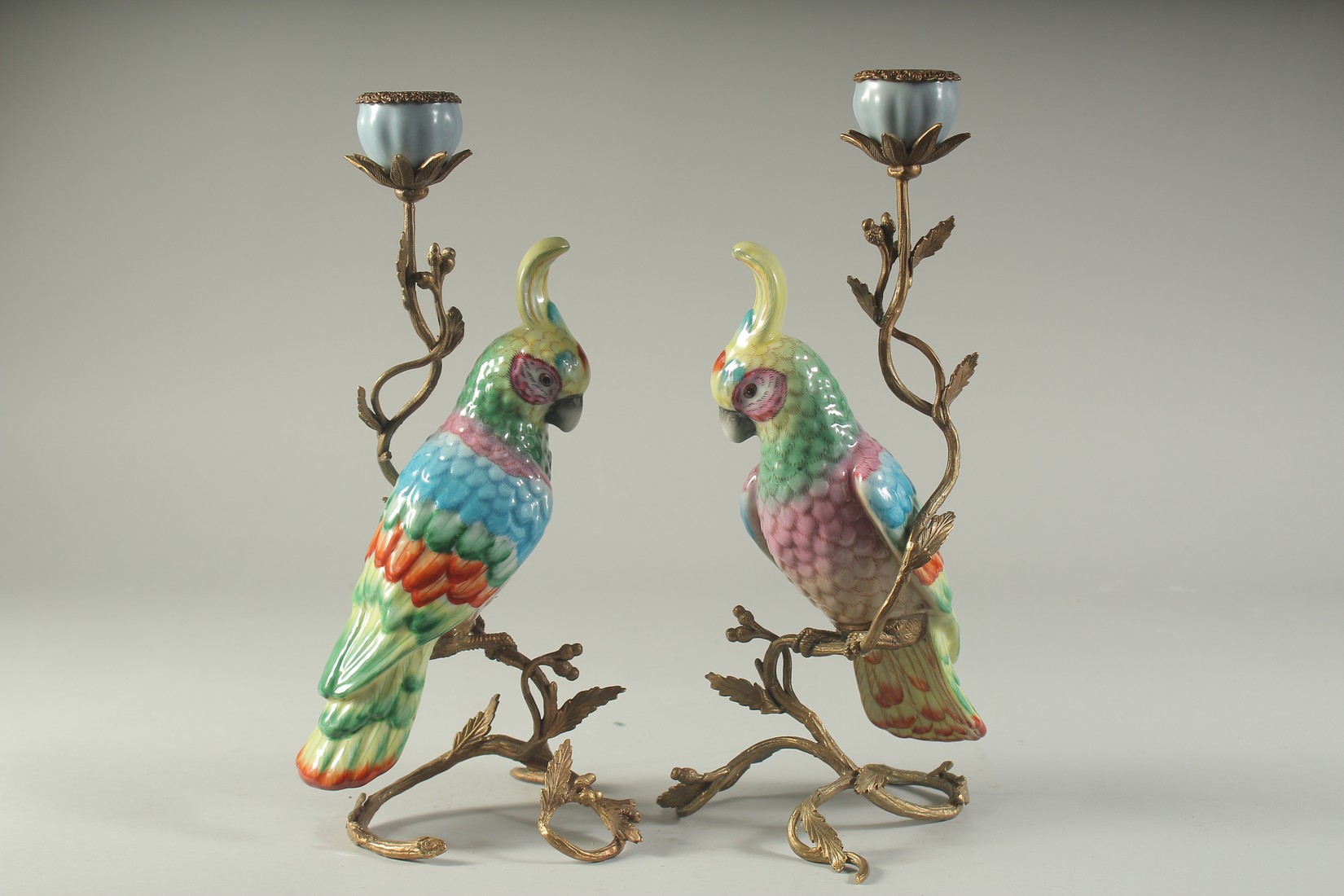 A PAIR OF SEVRES DESIGN PORCELAIN AND METAL PARROT CANDLESTICKS. 12ins high.